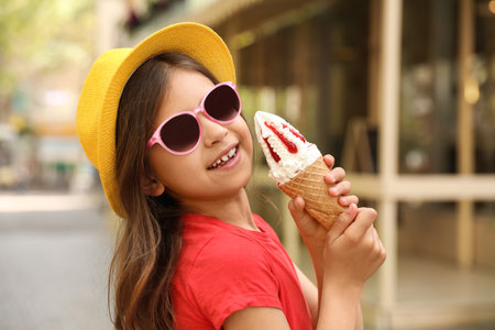 Cute little girl with delicious ice cream in the parkの写真素材