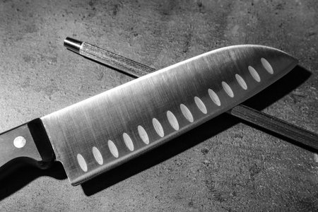 Santoku knife and sharpener on gray backgroundの写真素材