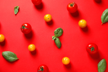 Flat lay composition with ripe cherry tomatoes and basil leaves on color backgroundの写真素材