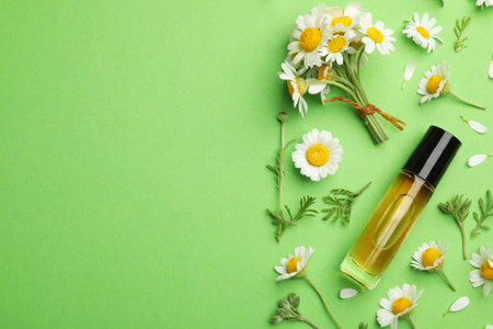 Flat lay composition with chamomile flowers and cosmetic bottle of essential oil on color background. Space for textの写真素材