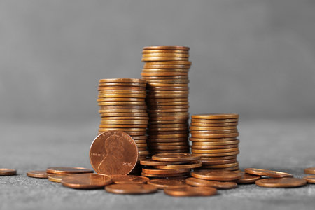 Stacks of coins on table against color background