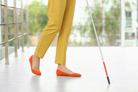 Blind person with long cane walking indoors, closeupの写真素材