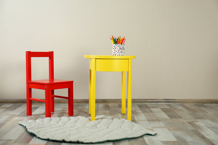 Chair and table with holder of color pencils in baby room interior. Space for textの写真素材