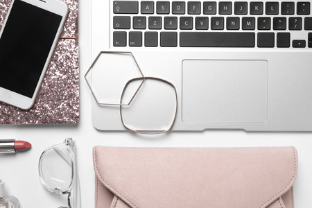 Flat lay composition with laptop, mobile phone and fashion blogger's stuff on white background