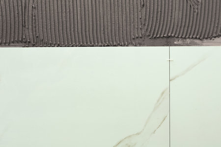 Adhesive mix and ceramic tiles on wall, top view. Space for textの写真素材