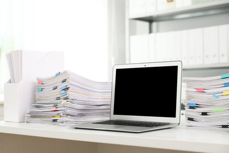 Laptop and documents on desk in office. Space for textの写真素材