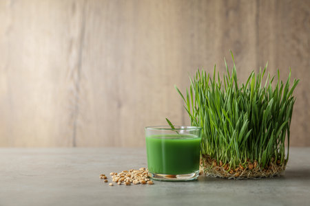 Glass of juice, sprouted wheat grass and grains on table. Space for textの写真素材