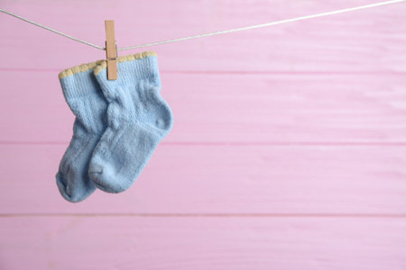 Pair of socks on laundry line against pink wooden background, space for text. baby accessoriesの写真素材