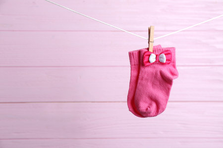 Pair of socks on laundry line against pink wooden background, space for text. baby accessoriesの写真素材