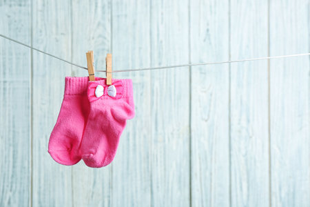Pair of socks on laundry line against wooden background, space for text. baby accessoriesの写真素材