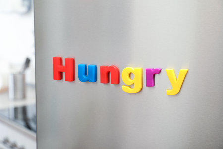 Word HUNGRY of magnetic letters on refrigerator door indoorsの写真素材