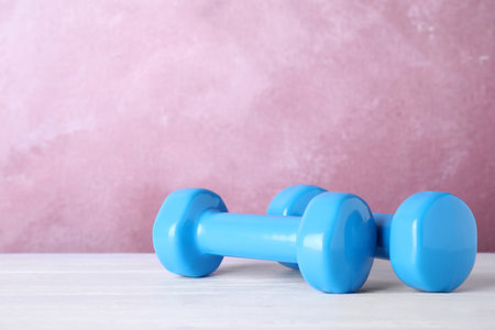 Stylish dumbbells on table against color background, space for text. home fitnessの写真素材
