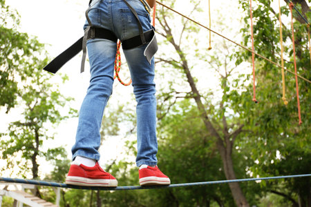 Little girl climbing in adventure park, closeup. summer campの写真素材