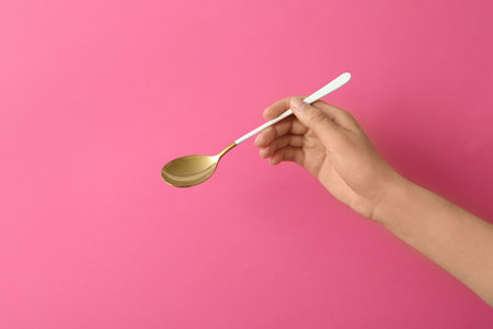 Woman holding empty table spoon on color background, closeupの写真素材