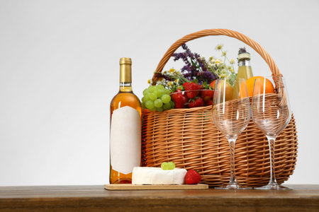 Picnic basket with wine and products on wooden table against white background. Space for textの写真素材