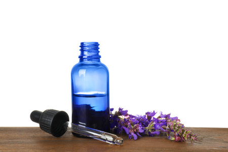 Bottle of herbal essential oil, pipette and sage flowers on wooden table, white backgroundの写真素材