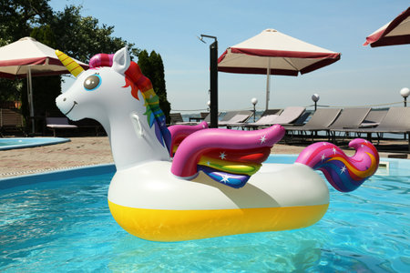 Funny inflatable unicorn ring floating in swimming pool on sunny day, outdoorsの写真素材