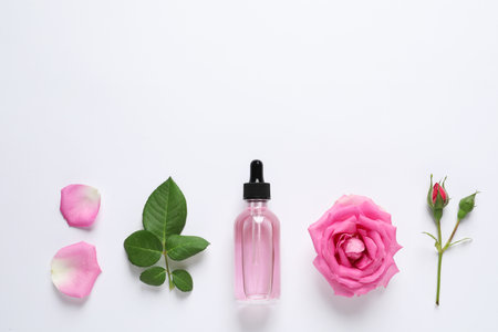 Composition with rose essential oil and flowers on white background, top viewの写真素材