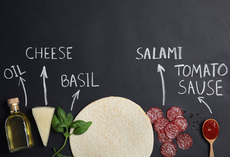Pizza crust, ingredients and chalk written product's names on black background, flat layの写真素材