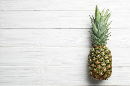 Fresh whole pineapple on white wooden background, top view. Space for textの写真素材
