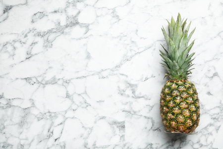 Fresh whole pineapple on white marble background, top view. Space for textの写真素材