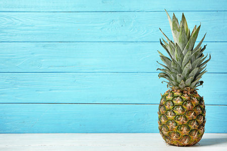 Fresh delicious pineapple on table against wooden background, space for textの写真素材