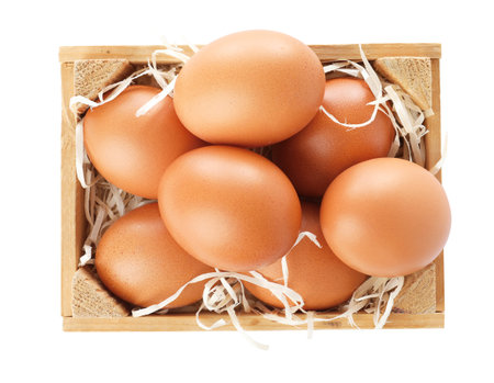 Wooden crate full of fresh eggs on white background, top viewの写真素材