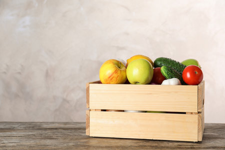 Wooden crate with fruits and vegetables on table, space for textの写真素材