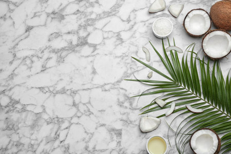 Bowl of natural organic oil and coconuts on marble background, flat lay. Space for textの写真素材
