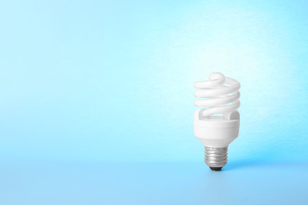 Modern fluorescent lamp bulb on light blue background, space for textの写真素材