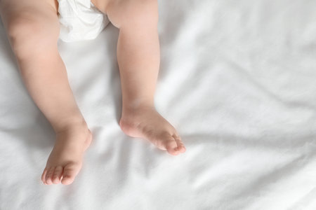 Little baby with cute feet on bed sheet, above view. Space for textの写真素材