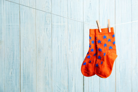 Pair of socks on laundry line against wooden background, space for text. baby accessories