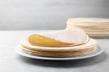 Plate with stack of tasty tortillas on gray table. Space for textの写真素材