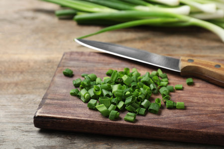 Wooden board with cut green onions on tableの写真素材
