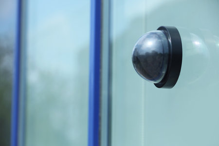 Modern CCTV security camera on building wall outdoors. Space for text