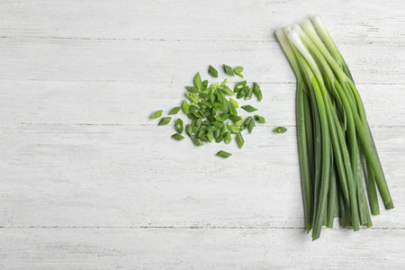 Cut and fresh green onions on white wooden table, flat lay with space for textの写真素材