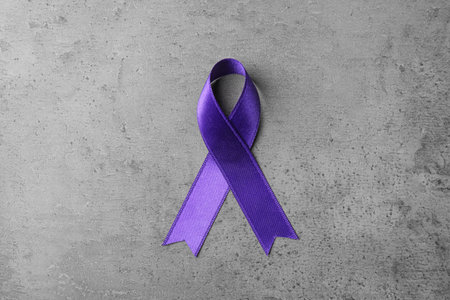 Purple ribbon on gray stone background, top view. domestic violence awarenessの写真素材