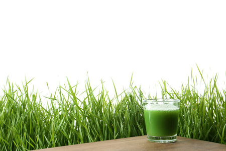 Glass of juice on table and fresh wheat grass against white background. Space for textの写真素材