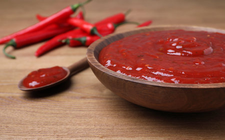 Plate and spoon of hot chili sauce on table, closeup. Space for textの写真素材