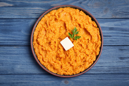 Plate with mashed sweet potatoes on wooden background, top viewの写真素材