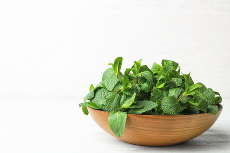 Wooden bowl with fresh green mint on table. Space for textの写真素材