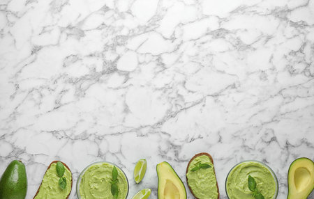 Flat lay composition with guacamole, sandwiches and avocados on white marble table. Space for textの写真素材