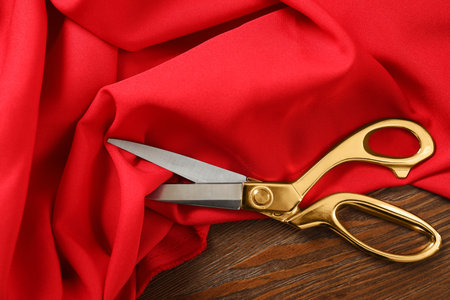 Red fabric and sharp scissors on wooden table, flat layの写真素材