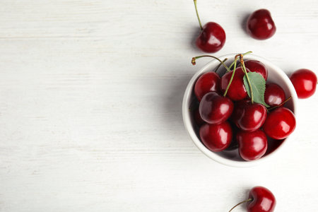 Bowl with sweet cherry on white wooden table, top view. Space for textの写真素材
