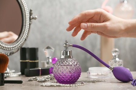 Woman reaching for crystal bottle of luxurious perfume on dressing table, closeup