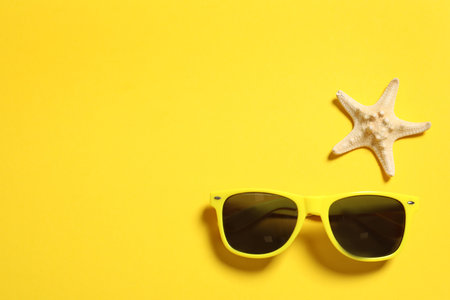 Sunglasses and starfish on color background, top view with space for text. beach accessoriesの写真素材