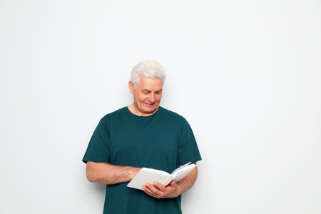 Senior man reading book on white background, space for textの写真素材