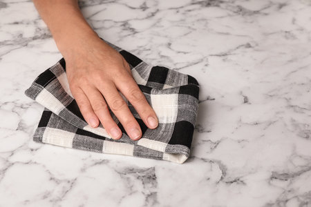 Woman wiping marble table with kitchen towel, closeupの写真素材