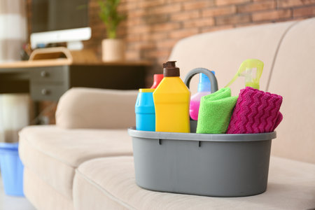 Basin with different detergents on sofa indoors, space for text. cleaning serviceの写真素材