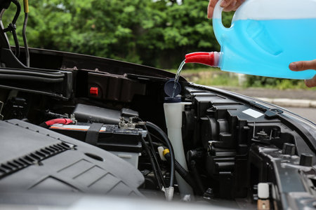 Man pouring liquid from plastic canister into car washer fluid reservoir, closeupの写真素材